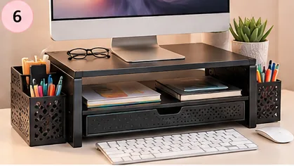 Black monitor stand with storage drawer and pen holders on a desk