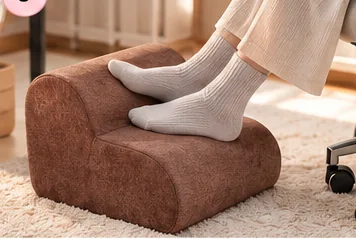 Brown ergonomic footrest supporting feet beneath a home office desk